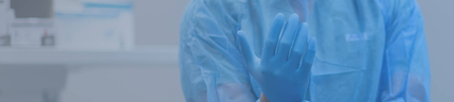 pulling on latex gloves while wearing a surgical gown