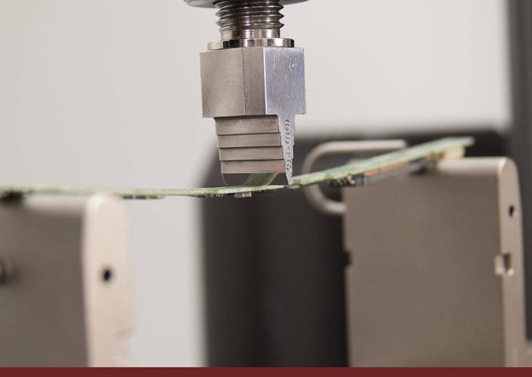Instron three-point bend fixture applying a load to a printed circuit board specimen during PCB bend testing