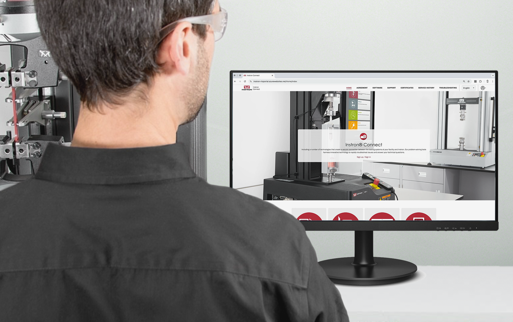 | Instron Lab technician viewing the Instron Connect Portal homepage on a monitor next to a testing system.