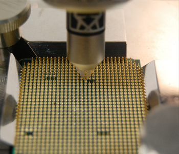 Close-up of a PCB socket with thousands of gold pins and a precision nozzle descending toward them.