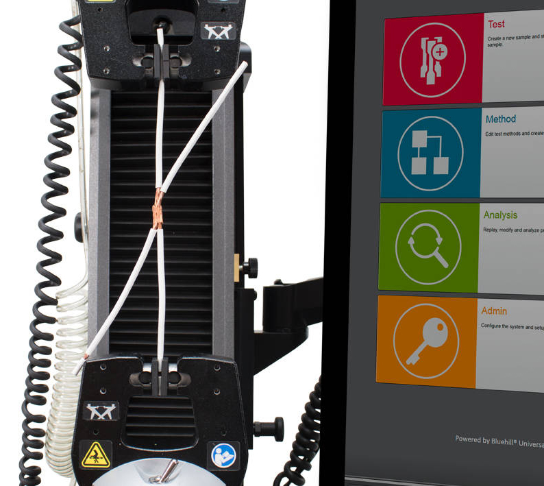 Spliced electrical wires held in Instron pneumatic side action grips for tensile testing, with the Bluehill Universal Software home screen displayed on a monitor. | Instron