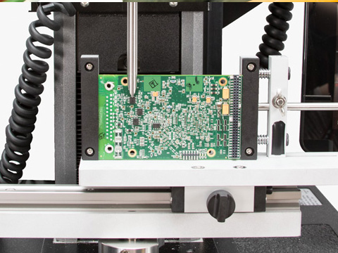 Green printed circuit board secured in a CNC machine during PCB milling.