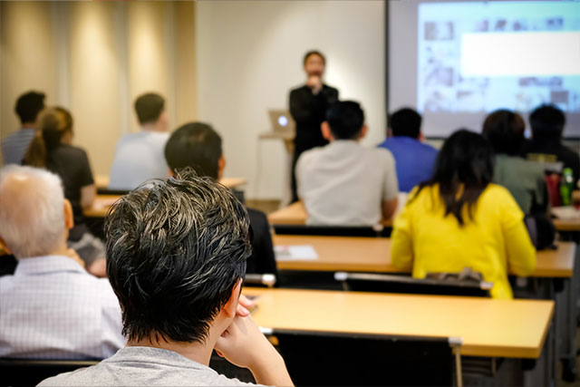 Attendees engaged in a classroom training session with an instructor presenting on a projector screen