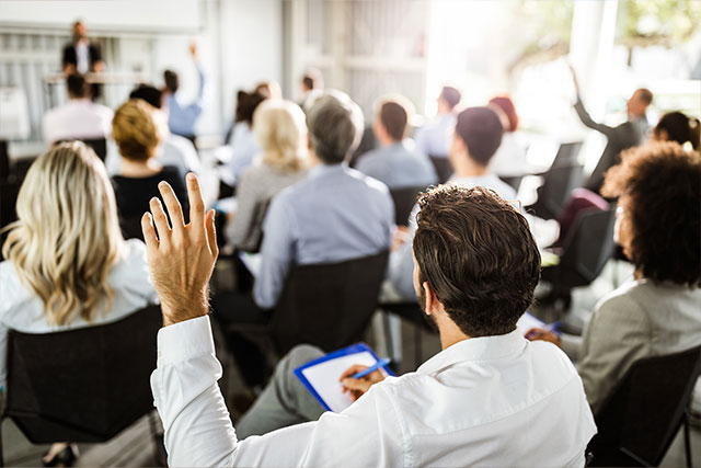 Training course attendee raising a hand to ask a question during a classroom session