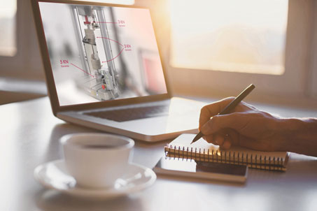 | Instron Eine Person nimmt an einem Online-Kurs auf einem Laptop teil und macht sich mit Stift und Notizblock Notizen. Neben dem Laptop ist eine Kaffeetasse zu sehen