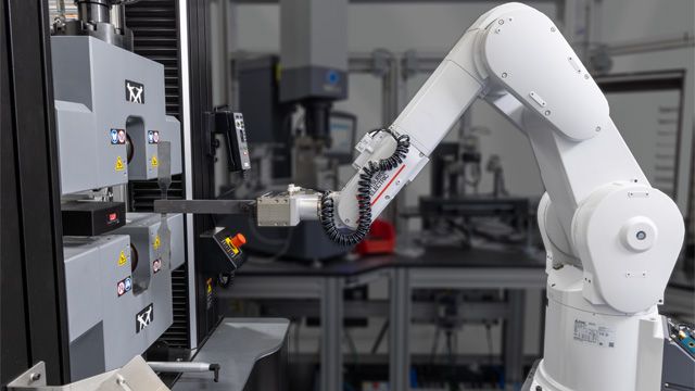 | Instron Industrial robot arm precisely loading a tensile specimen into hydraulic wedge grips on an Instron 68FM universal testing machine as part of the Instron AT6 automated testing system in a multi-system laboratory environment