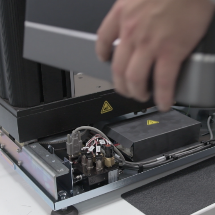 | Instron Instron technician servicing an internal component during preventive maintenance on a testing system.