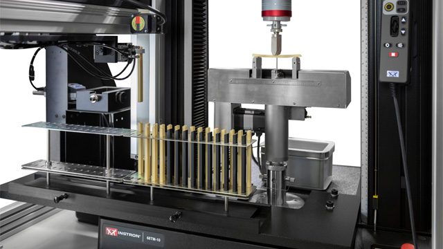 AT3 automated testing system with specimen rack loading flexure test specimens onto a 6800 Series 68TM-10 table model for automated plastics flexural testing. | Instron