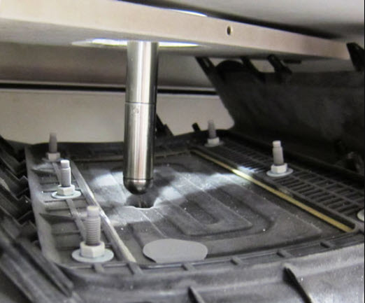 | Instron Close-up of an impact test tup positioned above a plastic automotive component during drop weight impact testing.