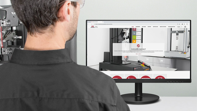 | Instron A man viewing a computer monitor with the Instron Connect Portal on the screen