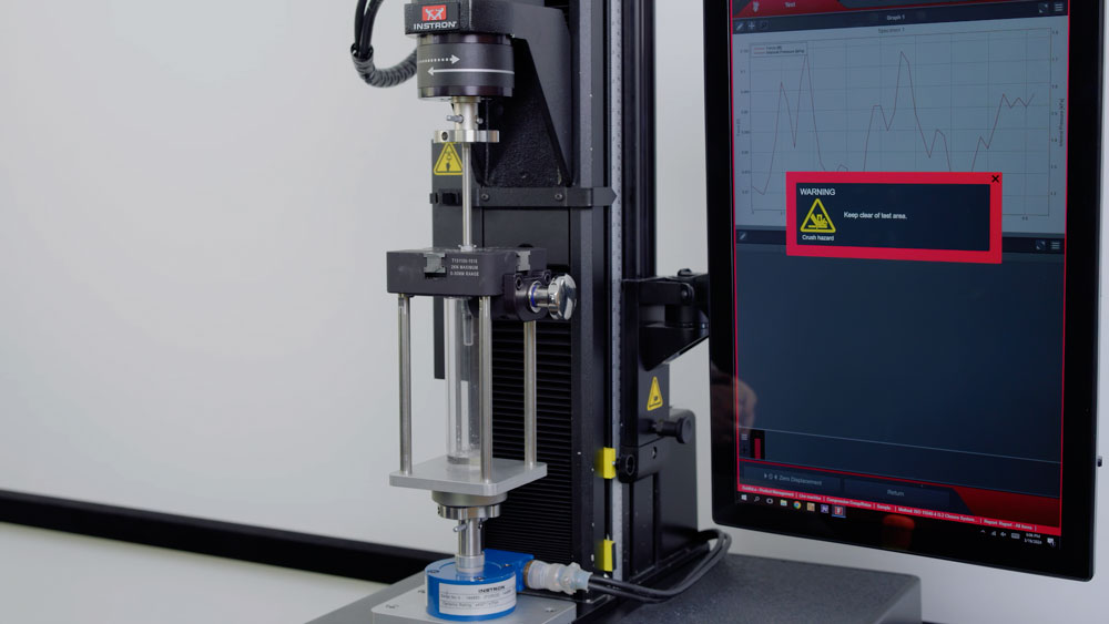 A universal syringe fixture mounted on an Instron testing system performs precision mechanical testing to evaluate syringe and injection device performance, reliability, and quality under controlled laboratory conditions. | Instron