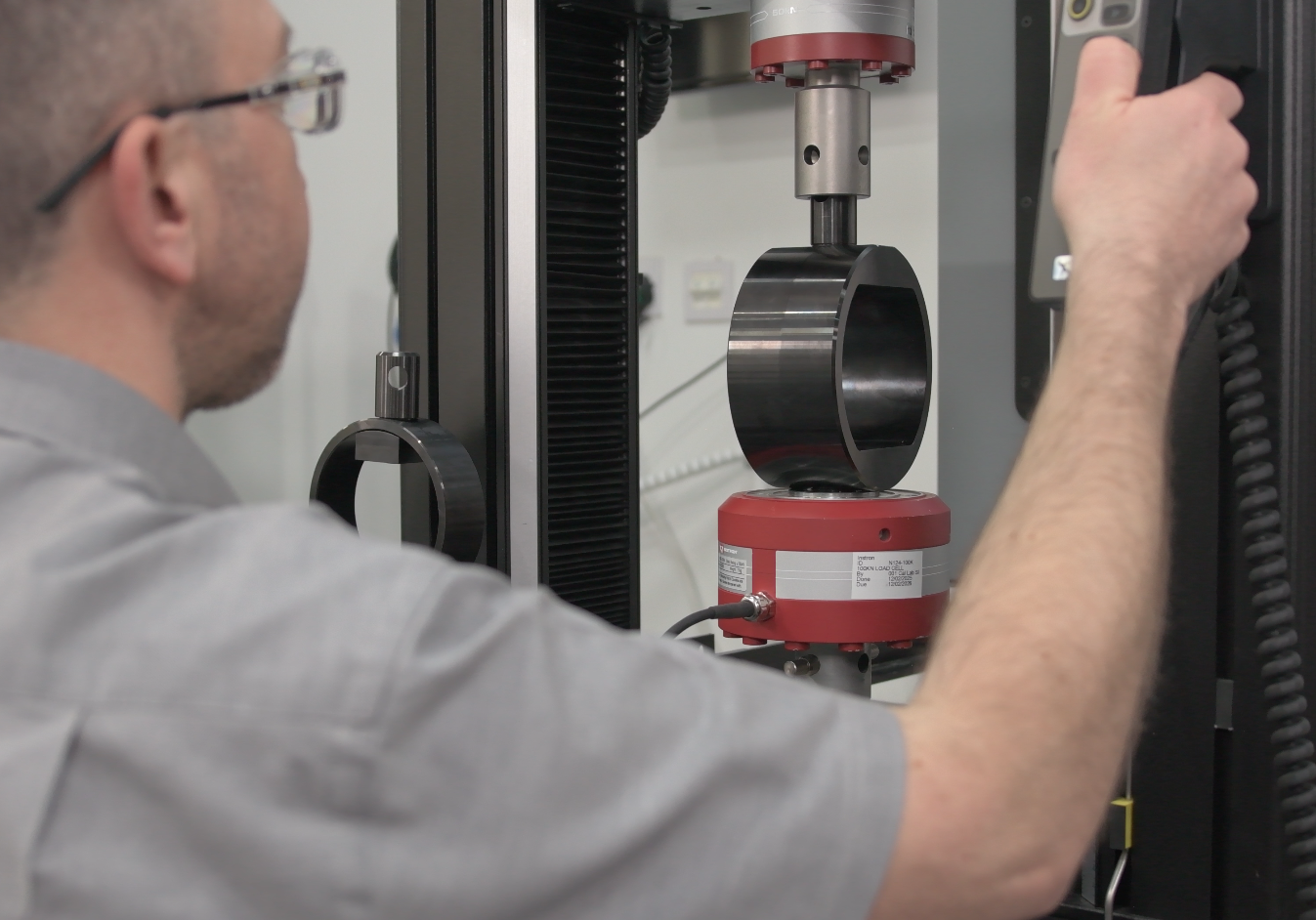 Instron field service engineer positioning a calibration fixture in a testing machine during force calibration.
