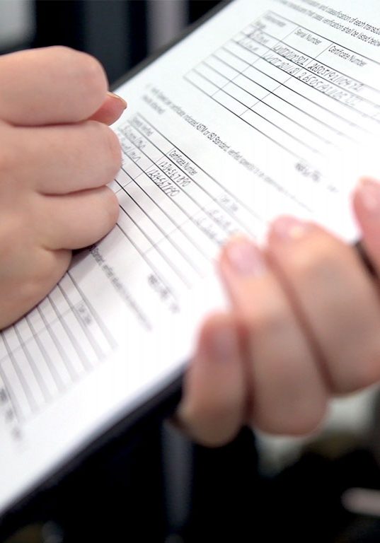 | Instron Hands holding a pen and clipboard with an IQOQ checklist on paper