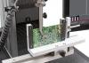 Instron universal testing system performing shear testing of a printed circuit board with a PCB fixture and operator dashboard visible